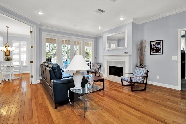 living room featuring ornamental molding, light hardwood / wood-style floors, and an inviting chandelier