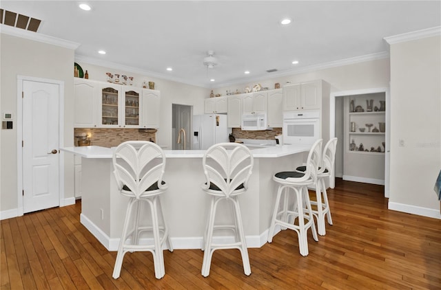 kitchen with white cabinets, white appliances, a breakfast bar area, and a large island with sink