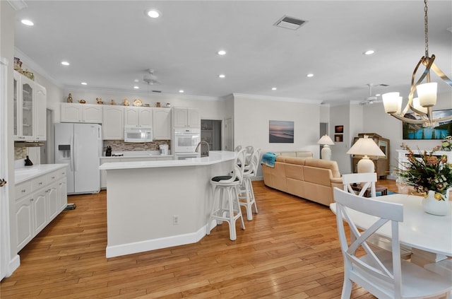 kitchen featuring white cabinetry, tasteful backsplash, white appliances, a kitchen island, and light wood-type flooring