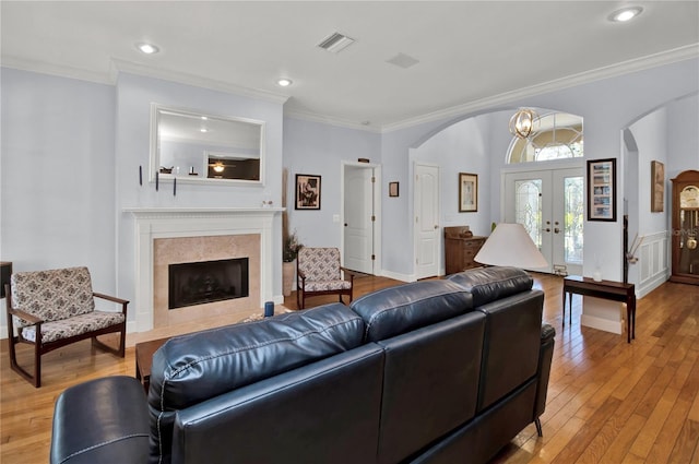 living room with a fireplace, french doors, hardwood / wood-style floors, and ornamental molding