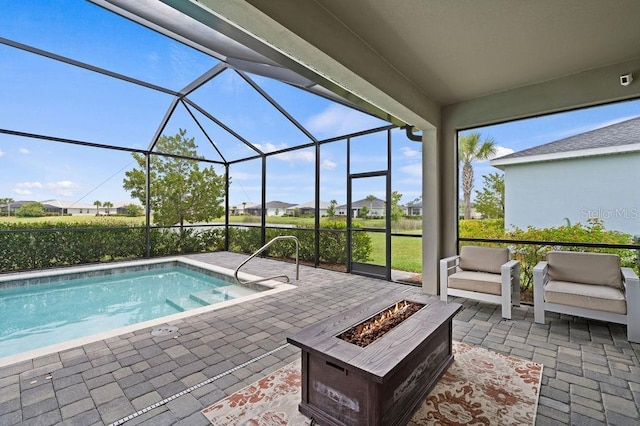 view of pool featuring glass enclosure, an outdoor living space with a fire pit, and a patio area