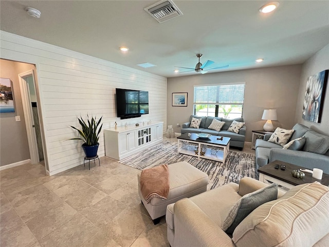 living room with ceiling fan and wooden walls