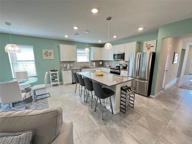 kitchen featuring pendant lighting, plenty of natural light, a center island, and appliances with stainless steel finishes