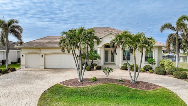 view of front facade featuring french doors, central AC, a water view, and a garage