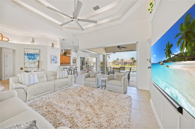 tiled living room with a tray ceiling, ceiling fan, a towering ceiling, and ornamental molding