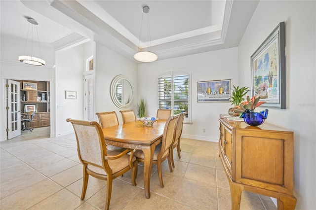 dining room featuring light tile patterned floors, baseboards, a tray ceiling, and ornamental molding