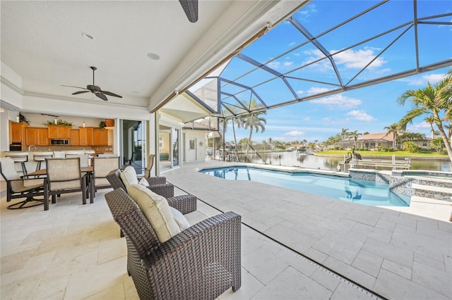 view of swimming pool with ceiling fan, a lanai, a water view, a patio area, and a pool with connected hot tub