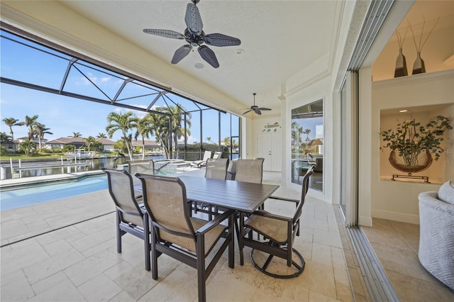 sunroom with ceiling fan and a water view