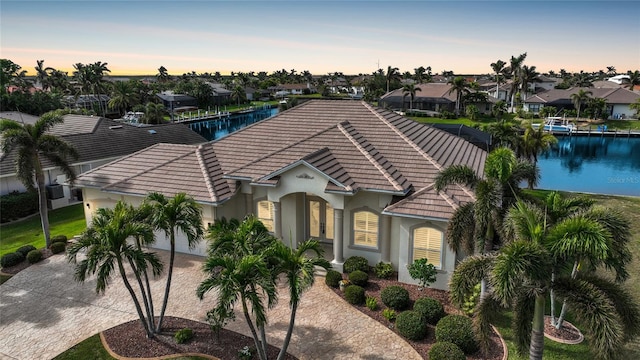 view of front of property with a garage, a tile roof, a residential view, decorative driveway, and stucco siding