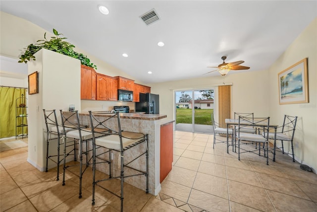 kitchen featuring a breakfast bar, black appliances, ceiling fan, light tile patterned flooring, and kitchen peninsula