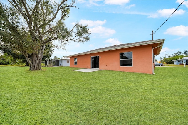 rear view of house featuring a lawn and a patio