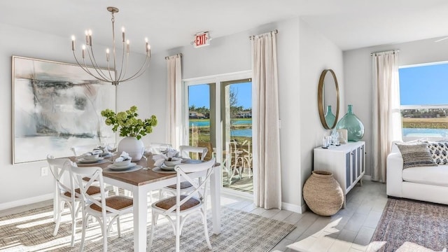 dining space with hardwood / wood-style flooring, a notable chandelier, and a water view