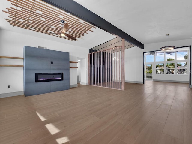 unfurnished living room with wood-type flooring, ceiling fan, and beam ceiling