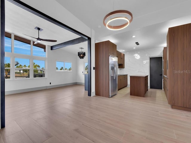 kitchen with ceiling fan, stainless steel fridge, pendant lighting, light hardwood / wood-style floors, and a kitchen island