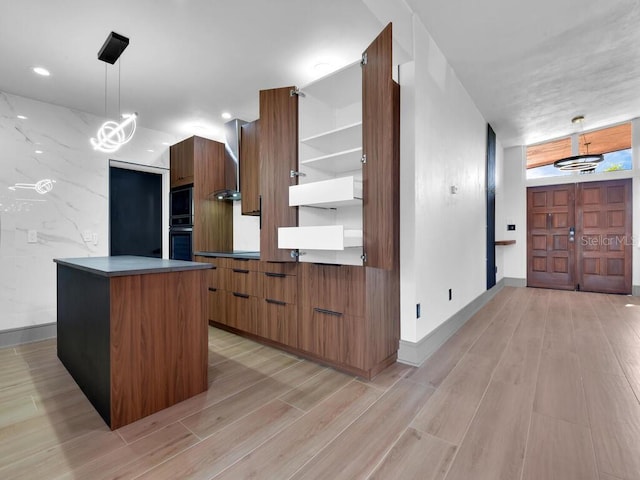 kitchen featuring light hardwood / wood-style flooring, a kitchen island, hanging light fixtures, and black double oven