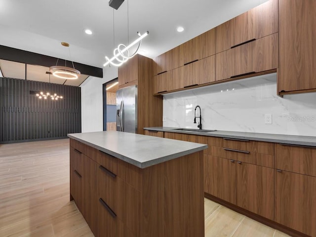 kitchen with sink, stainless steel refrigerator with ice dispenser, pendant lighting, decorative backsplash, and light wood-type flooring