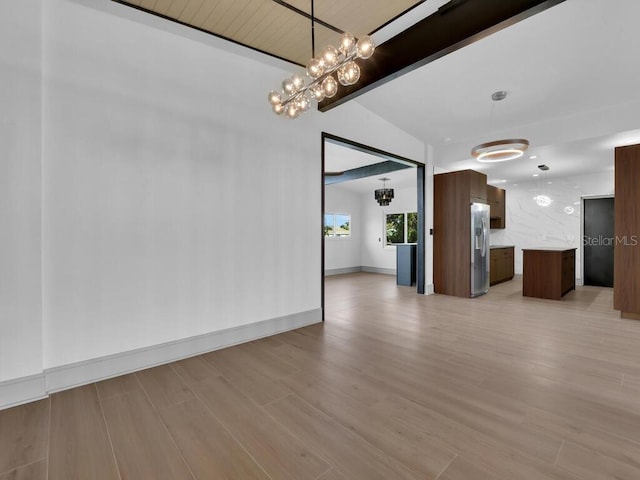 unfurnished dining area featuring a notable chandelier, lofted ceiling with beams, and light hardwood / wood-style flooring