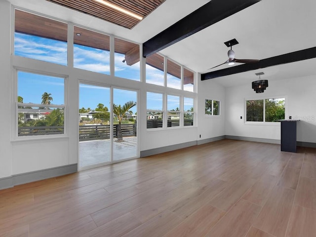 unfurnished living room with beamed ceiling, light hardwood / wood-style flooring, a wealth of natural light, and ceiling fan