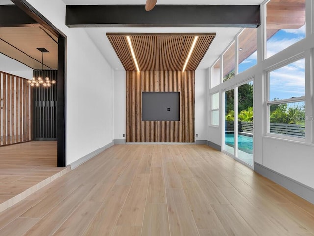 unfurnished living room with light hardwood / wood-style flooring, beamed ceiling, and ceiling fan with notable chandelier