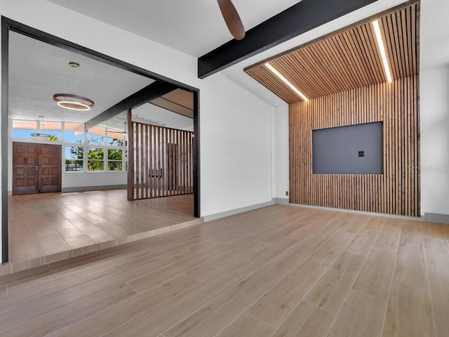 unfurnished living room with ceiling fan, light hardwood / wood-style floors, and lofted ceiling with beams