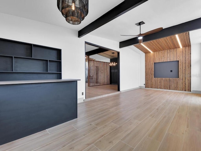 unfurnished living room with ceiling fan, wood walls, light wood-type flooring, and lofted ceiling with beams