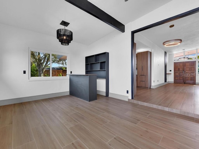 unfurnished living room with wood-type flooring, lofted ceiling with beams, and an inviting chandelier