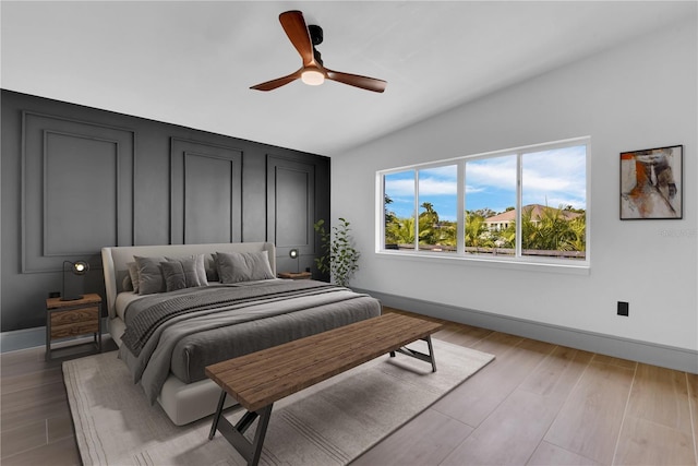 bedroom with ceiling fan, light hardwood / wood-style flooring, and lofted ceiling