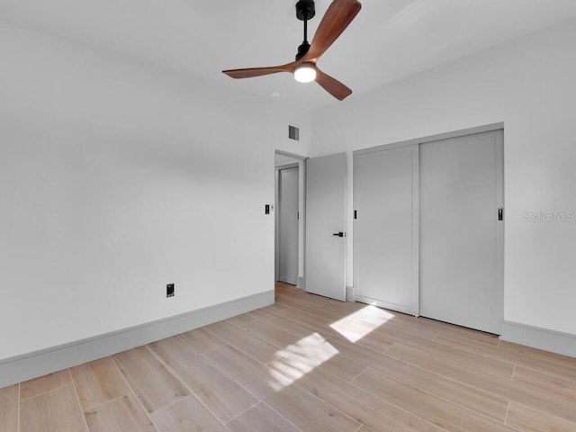 unfurnished bedroom featuring ceiling fan, light hardwood / wood-style floors, and a closet