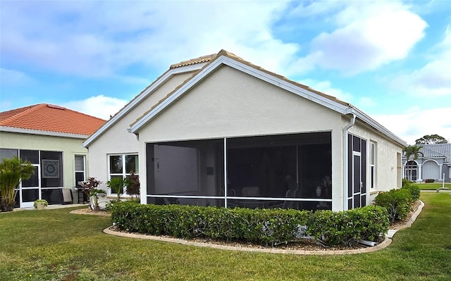 rear view of property featuring a lawn and a sunroom