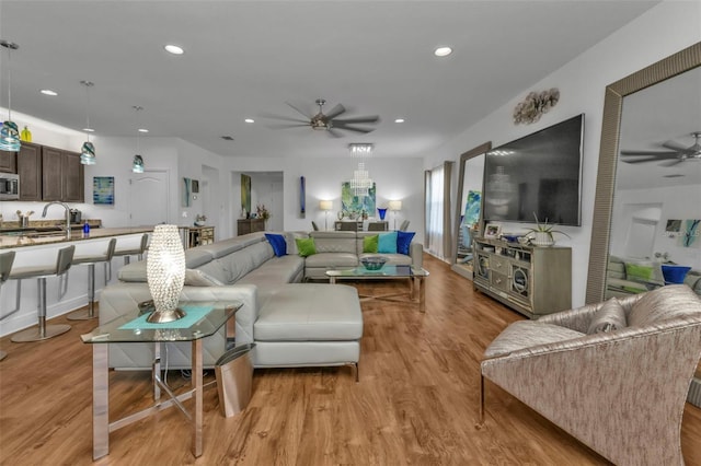 living room featuring sink, ceiling fan, and light wood-type flooring