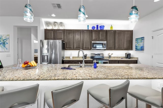 kitchen with a large island, appliances with stainless steel finishes, sink, and decorative light fixtures