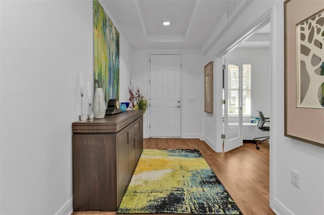 entryway with light hardwood / wood-style floors and a tray ceiling