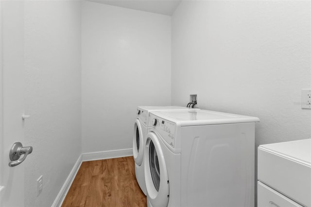 clothes washing area with light hardwood / wood-style floors and washing machine and dryer