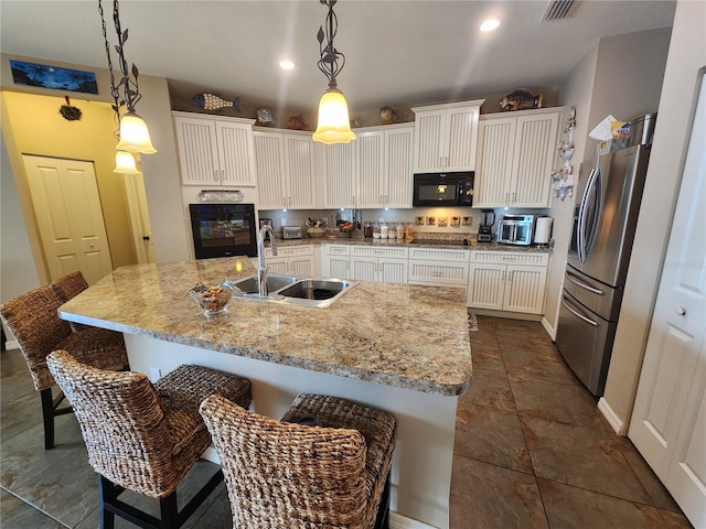 kitchen with pendant lighting, sink, an island with sink, and black appliances