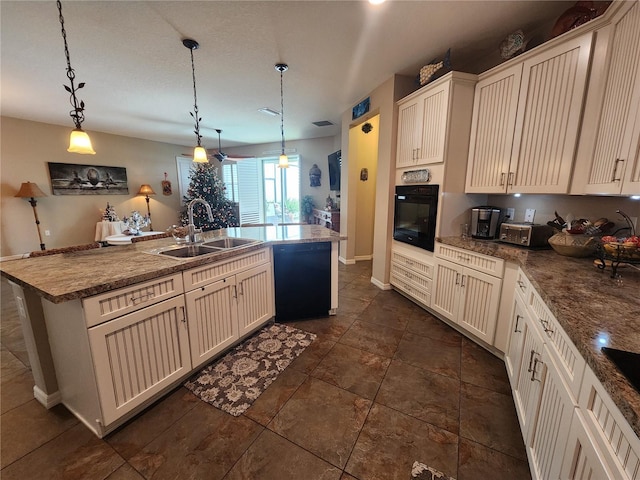 kitchen with pendant lighting, black appliances, sink, and a kitchen island with sink