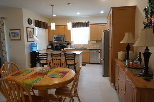 kitchen with sink, hanging light fixtures, stainless steel appliances, tasteful backsplash, and light stone counters