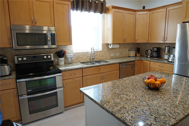 kitchen featuring light stone countertops, decorative backsplash, stainless steel appliances, and sink