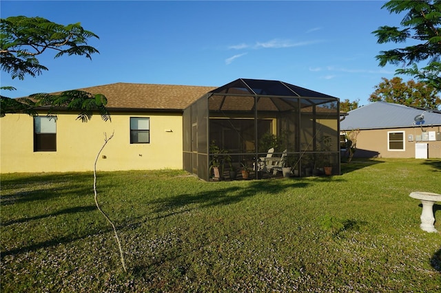 rear view of house with glass enclosure and a yard