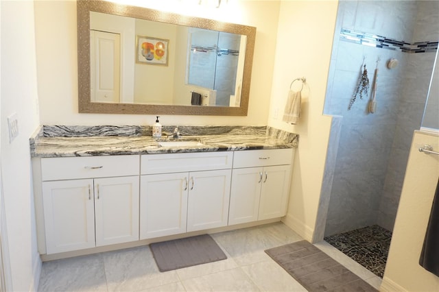 bathroom with a tile shower, tile patterned flooring, and vanity