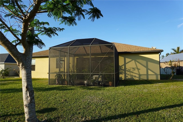 back of property with glass enclosure and a yard