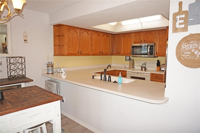 kitchen featuring wood-type flooring, white electric range, a chandelier, and sink