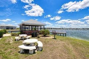 dock area featuring a gazebo, a water view, and a lawn