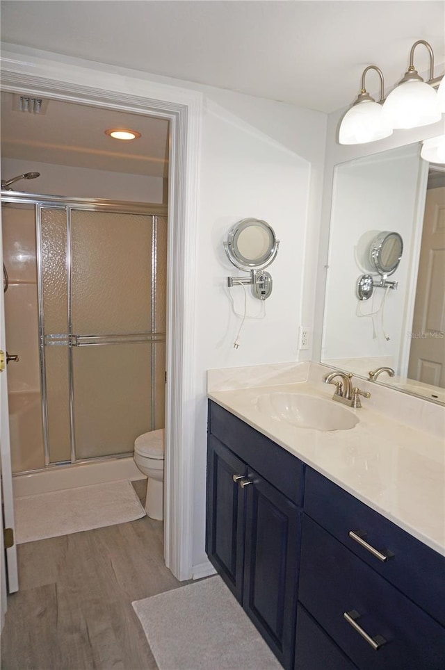 bathroom featuring walk in shower, vanity, toilet, and wood-type flooring