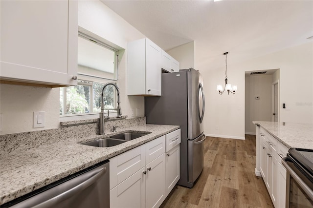 kitchen with white cabinets, sink, light hardwood / wood-style floors, light stone counters, and stainless steel appliances