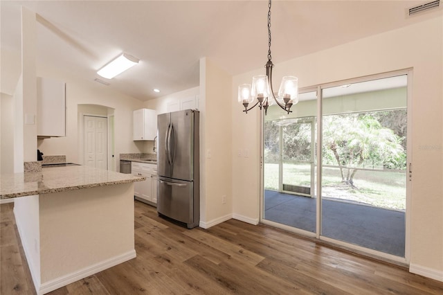 kitchen featuring kitchen peninsula, appliances with stainless steel finishes, hardwood / wood-style floors, white cabinetry, and hanging light fixtures