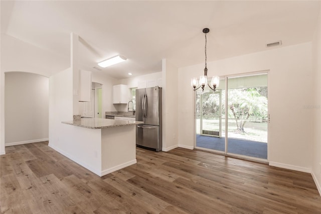 kitchen with white cabinetry, kitchen peninsula, stainless steel refrigerator, and dark wood-type flooring