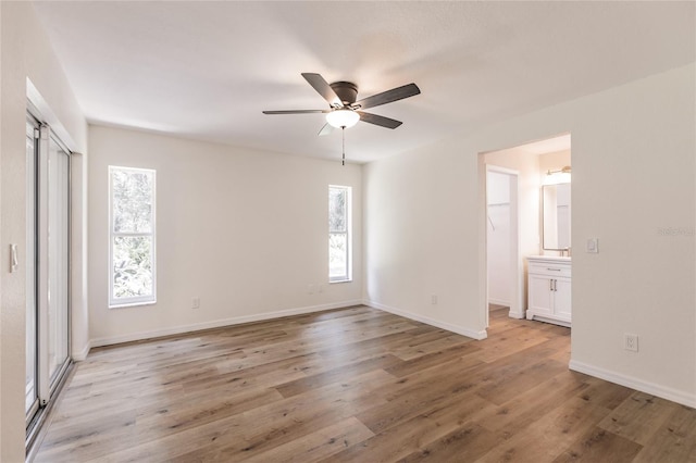 unfurnished bedroom with ceiling fan, light wood-type flooring, and ensuite bathroom