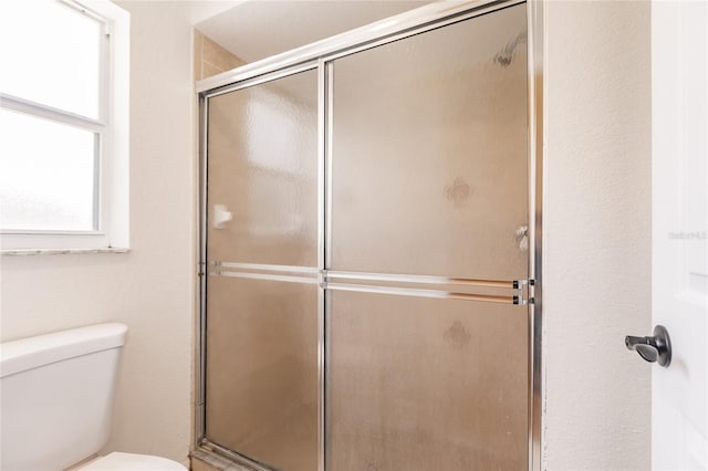 bathroom featuring toilet and an enclosed shower