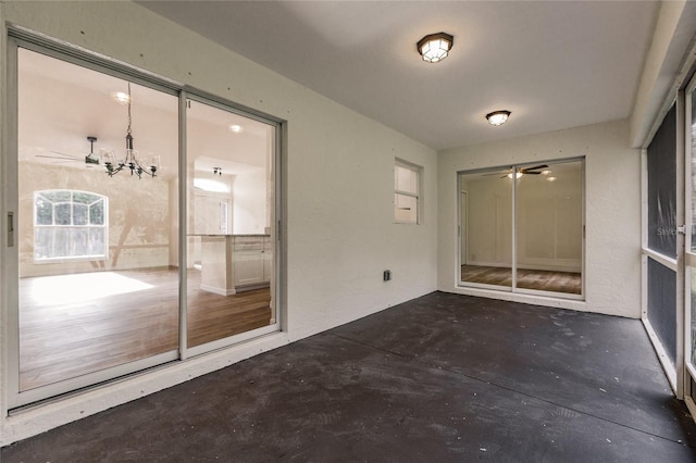 unfurnished sunroom featuring ceiling fan with notable chandelier