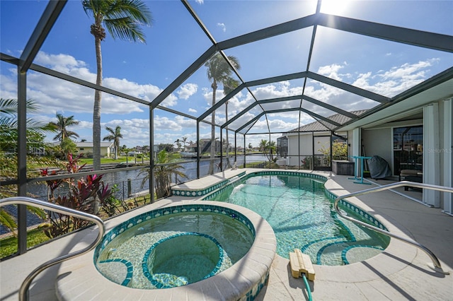 view of pool with a lanai, a water view, and an in ground hot tub